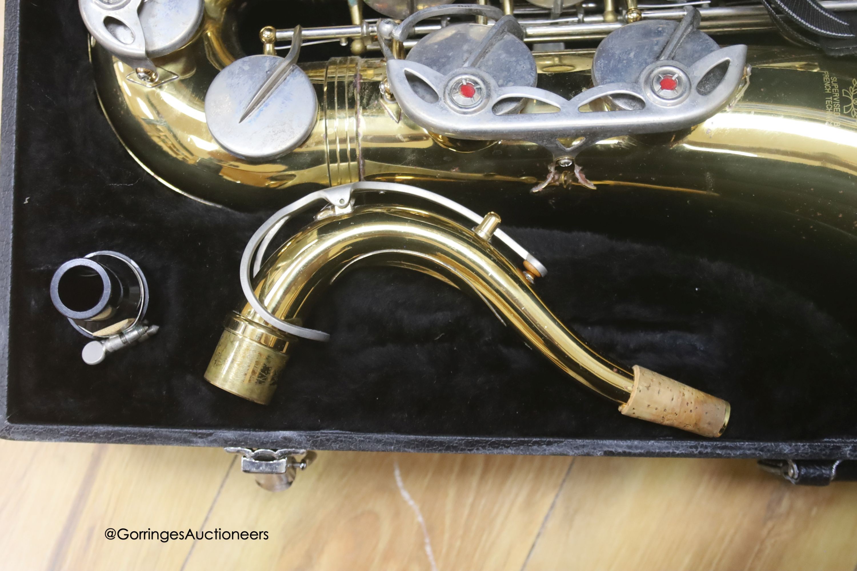 A cased Earlham brass saxophone and music sheets